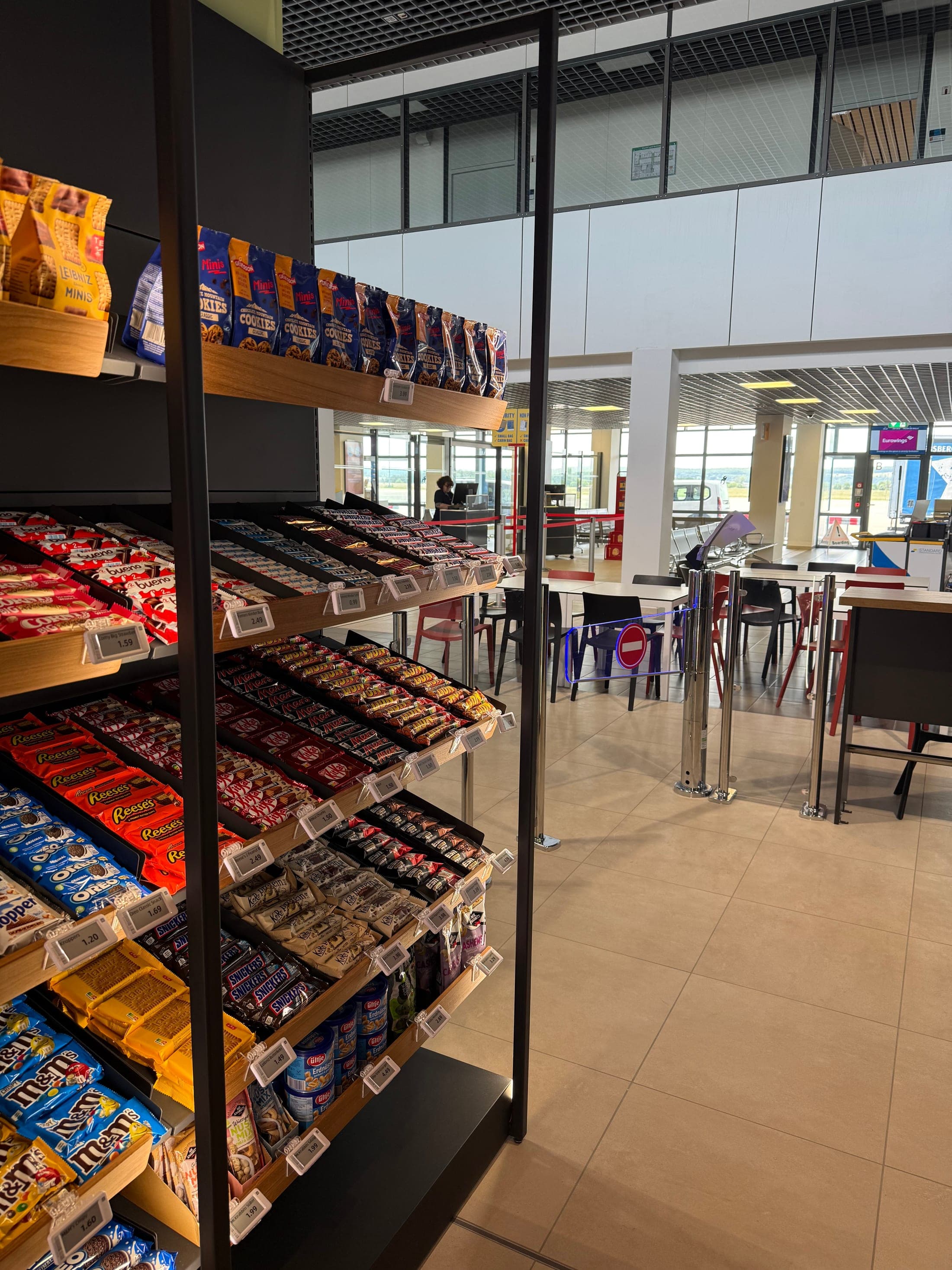 24/7-Shop am Flughafen Saarbrücken — Süßwarenauswahl vor der Glasfront des Terminals
