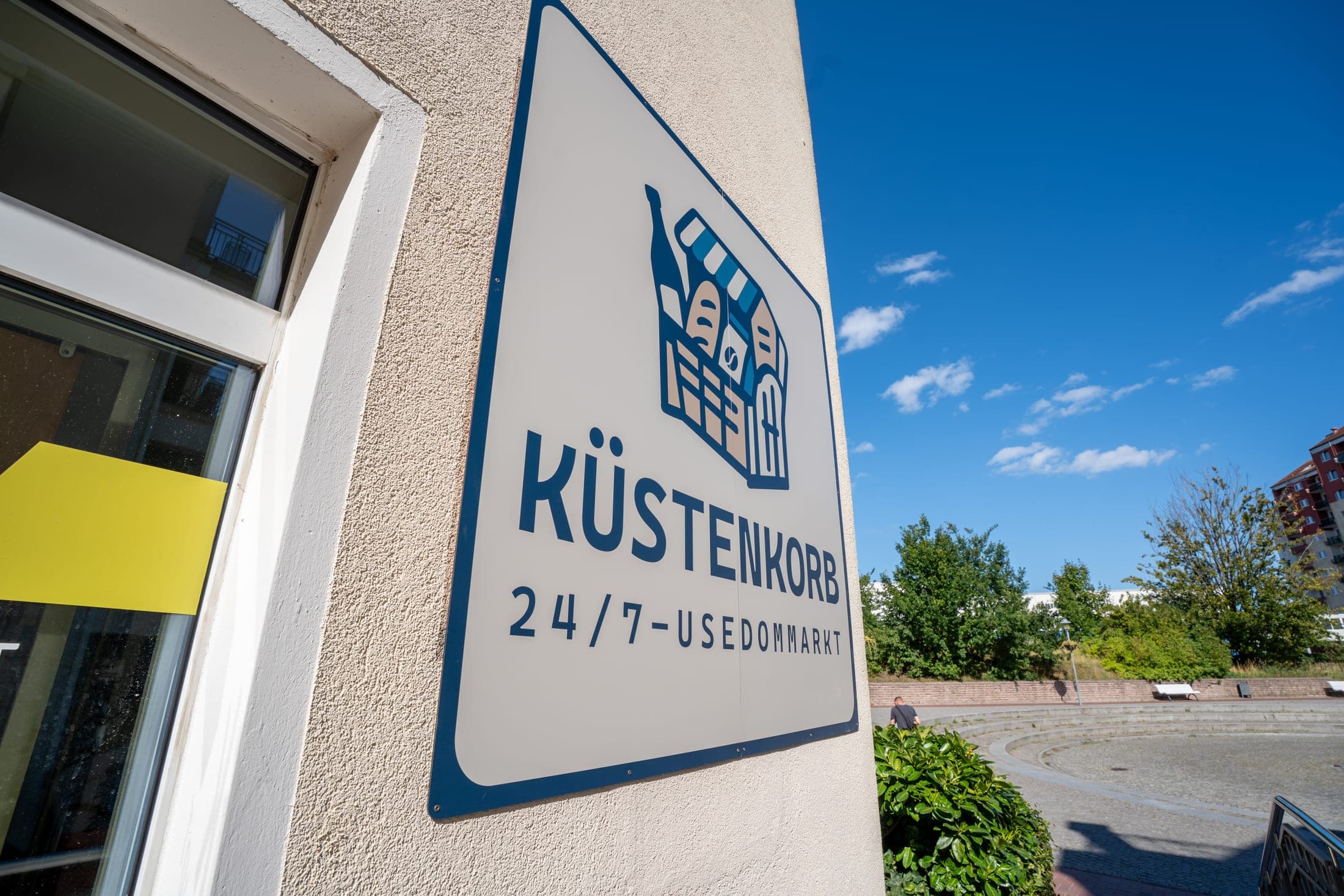 Küstenkorb 24/7-Usedommarkt — Außenschild am Gebäude auf Usedom
