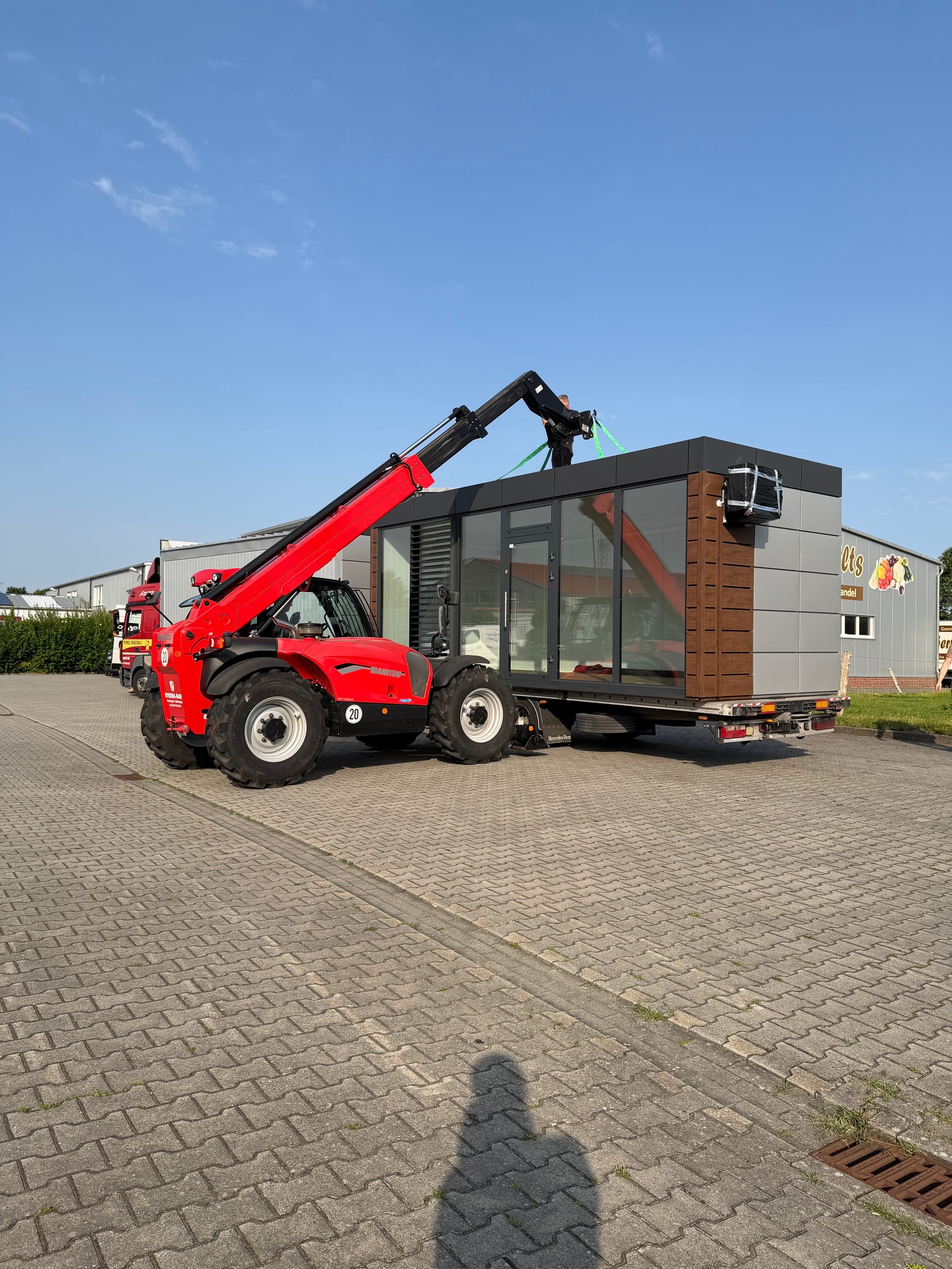 Anlieferung des Shop-Containers bei Albert Wilts in Upgant-Schott — ein Teleskoplader setzt den Container vom Tieflader ab