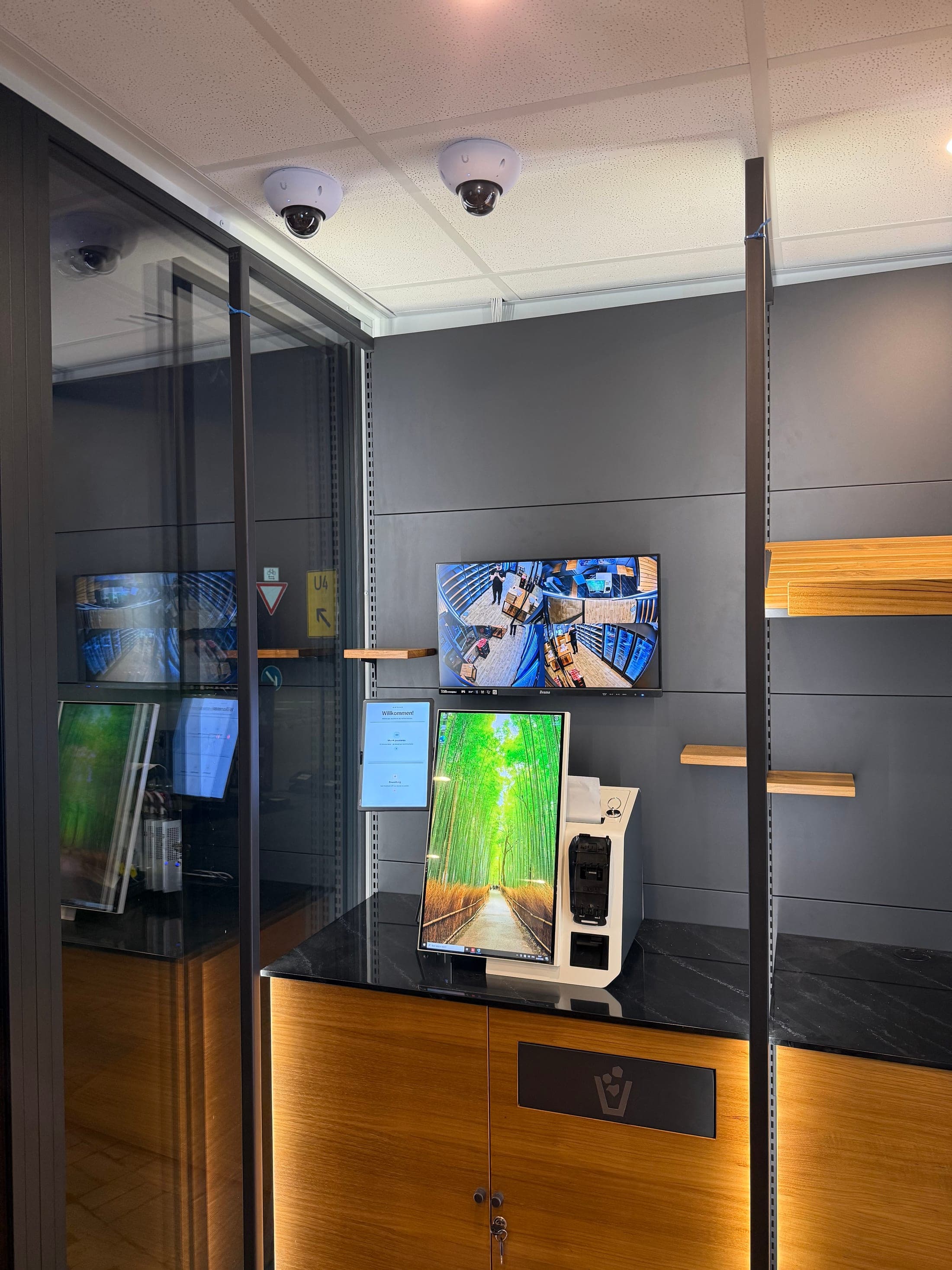 Eingangsbereich des Shop-Containers mit Deckenkameras, Live-Monitor der Kameraüberwachung und Sentra AI SmartStore Self-Checkout