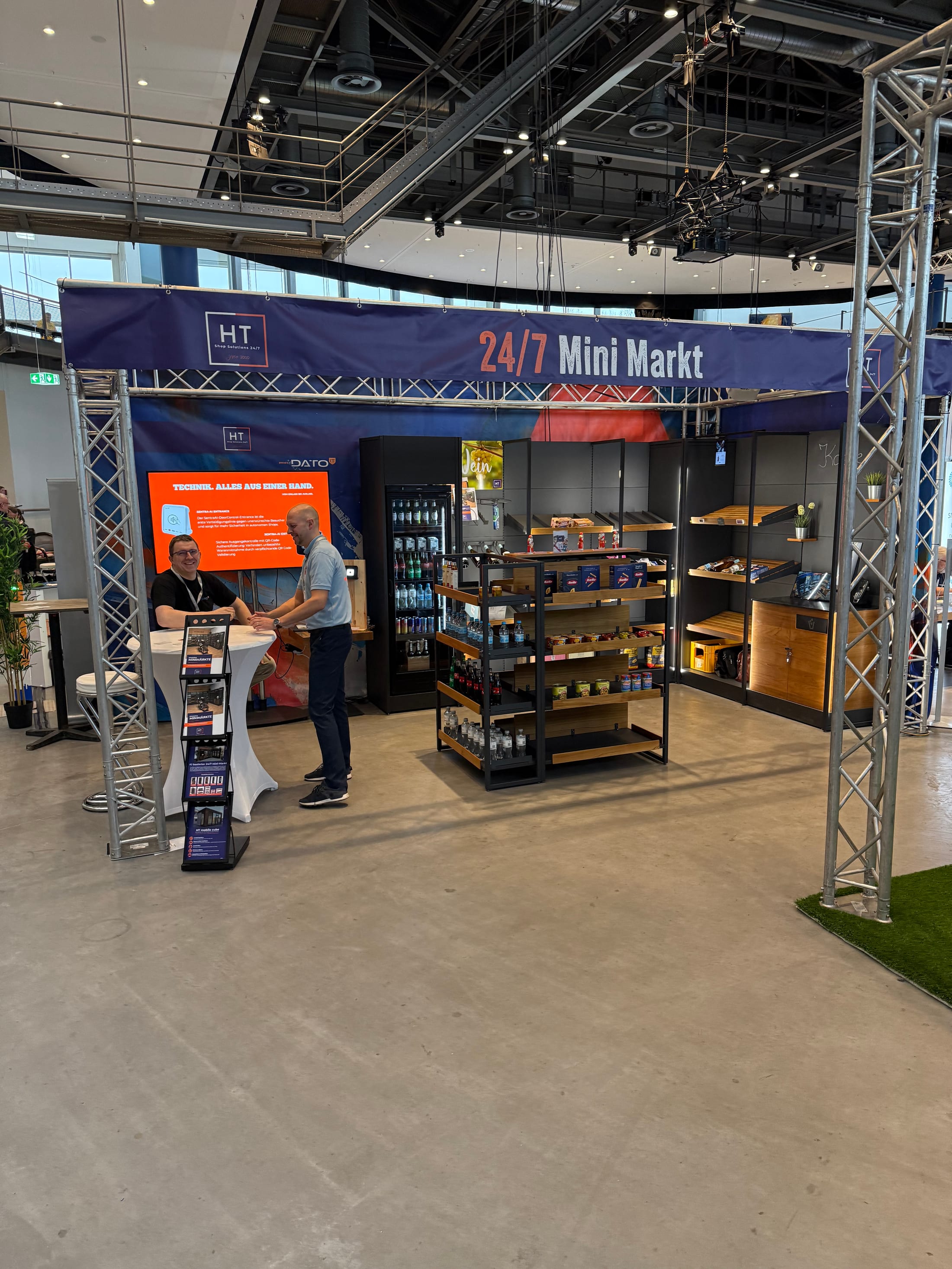 Autonomer 24/7-Mini-Markt am NCT-2025-Stand: Regale mit Snacks und Getränken unter dem Banner „24/7 Mini Markt“